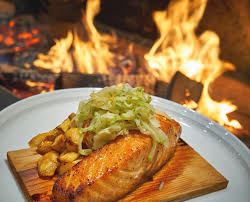  Photo of a fish dinner from Forge and Vine next to the flames from the wood fired oven